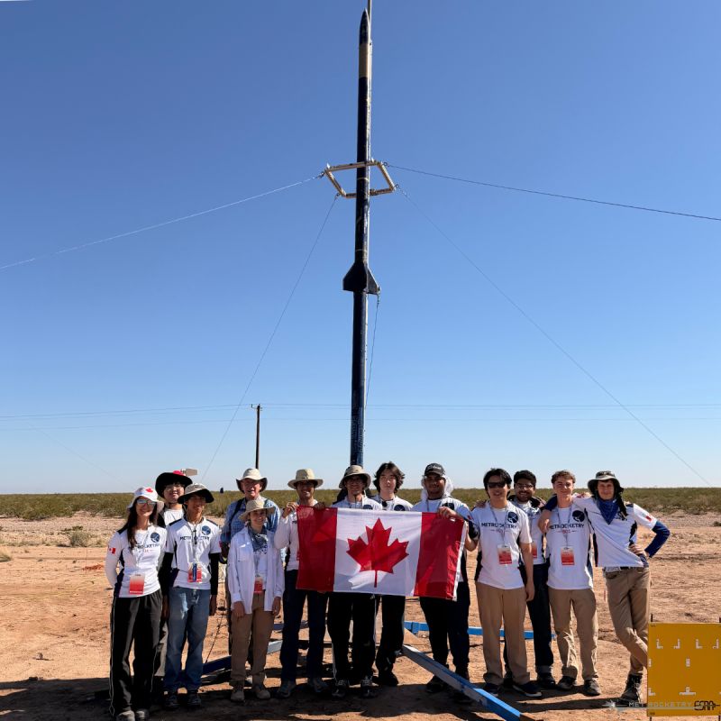 Met Rocketry team with a Canadian flag and their rocket at the launch pad